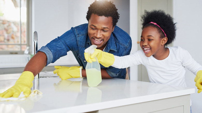Man and girl cleaning countertops