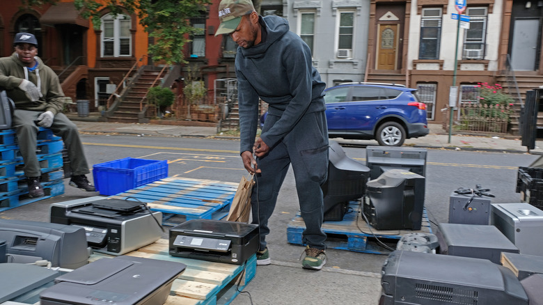 People in a neighborhood sort through donated electronics outside