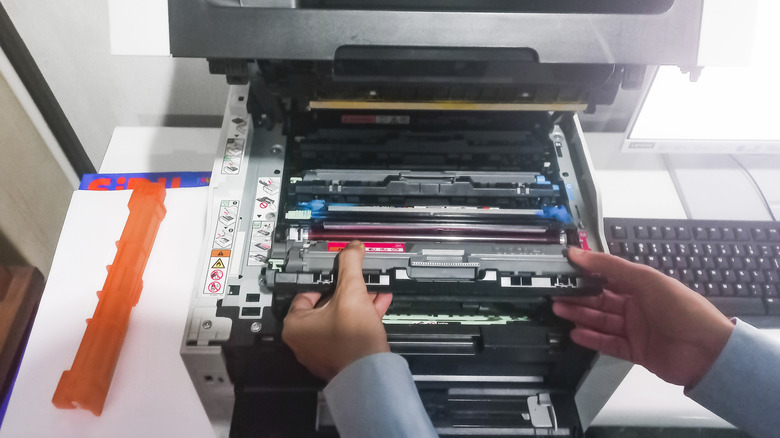 A person reloads the cartridges in a color laser printer