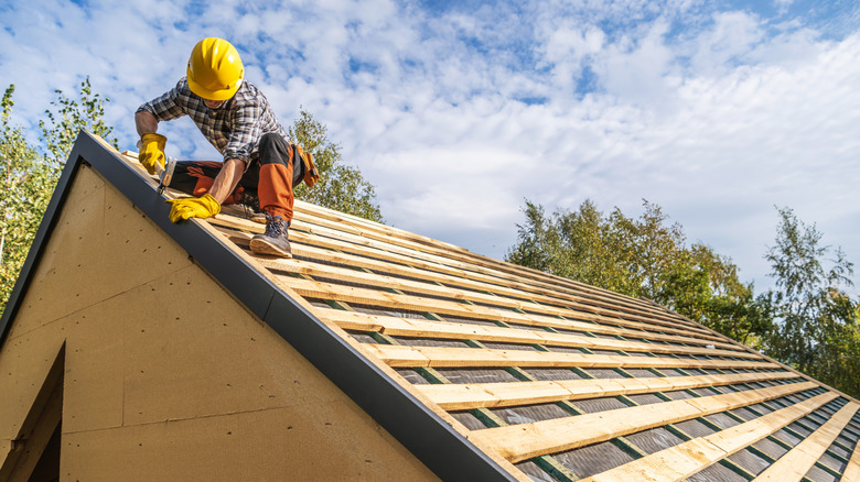 Roofer on roof working on wooden framing
