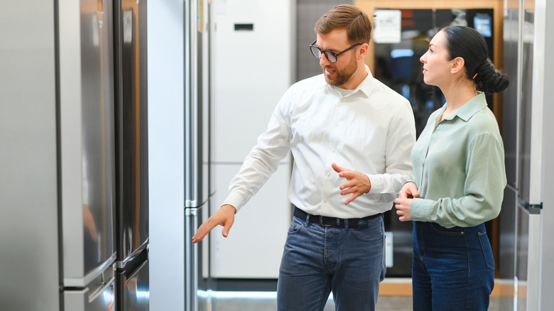 Shop assistant helping walk a woman learn more about fridges