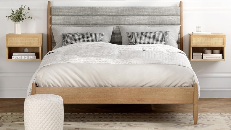 A neutral bed flanked by two floating bedside tables.
