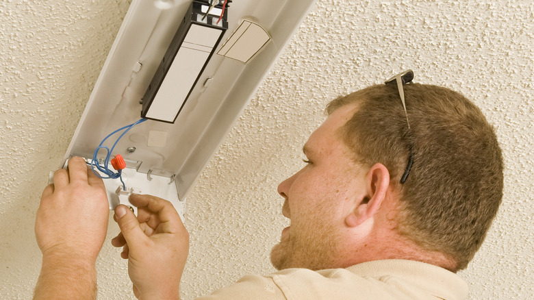 man fixing fluorescent light