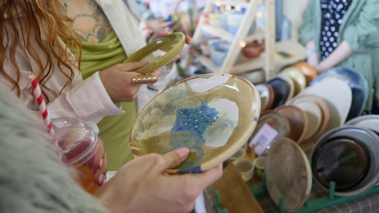 Two women holding ceramic dishes in their hands at a thrift store