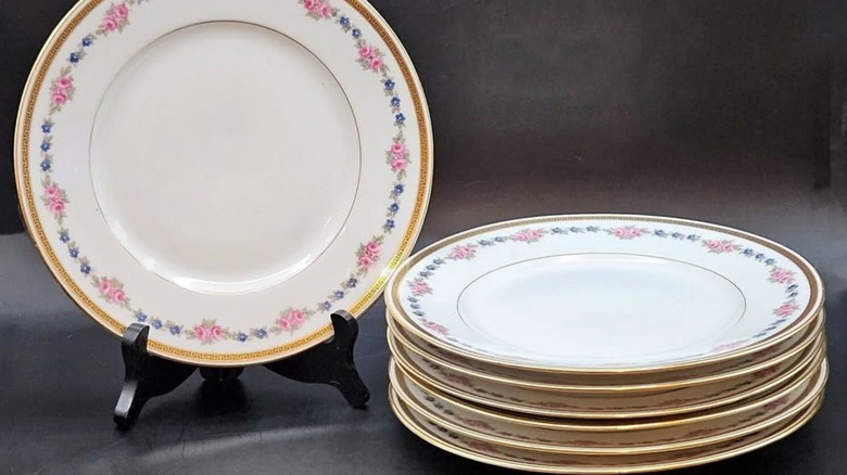 A stack of Bernardaud china plates with floral motifs