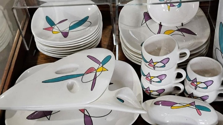 A display of Metlox California Mobile dishes on a shelf in an antique store.