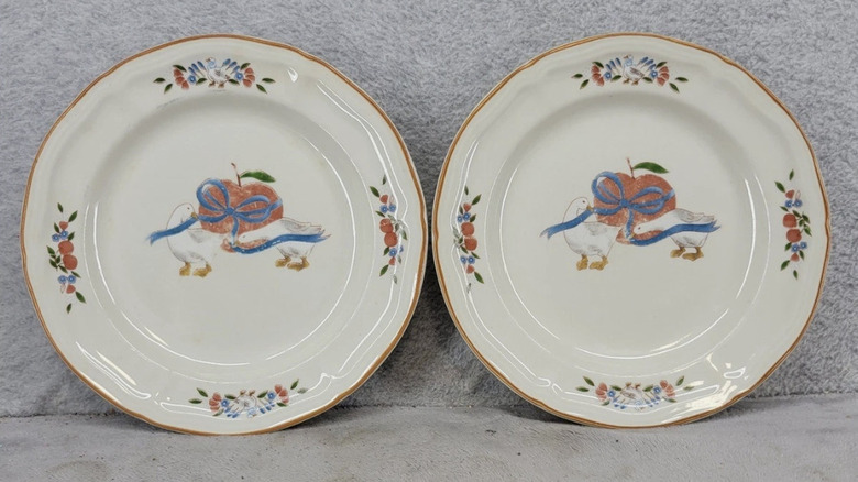 Two plates featuring a pattern of two geese tying a ribbon on an apple