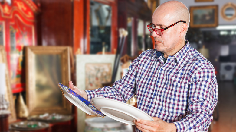 A man looking at plates in an antique store