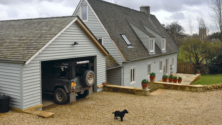 A Jersey Shore gravel driveway leads up to a blue-paneled house