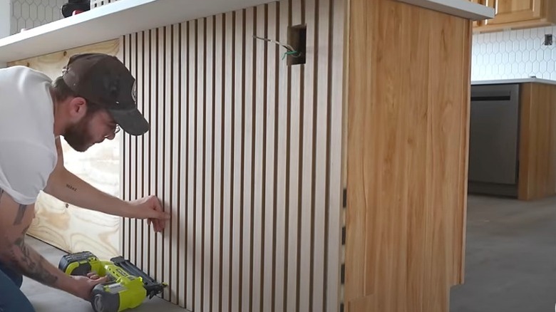 man nailing fluted panels to back of kitchen island