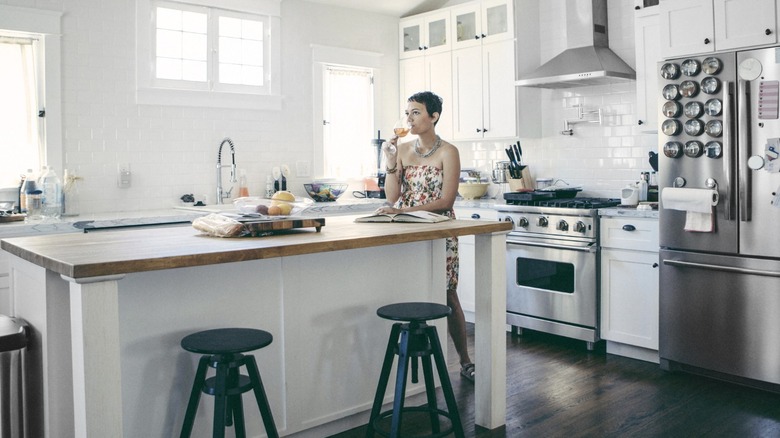 woman drinking wine at island counter in modern kitchen