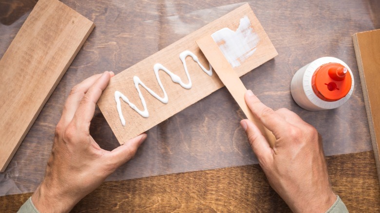 bird's eye view of man spreading wood glue on wood board