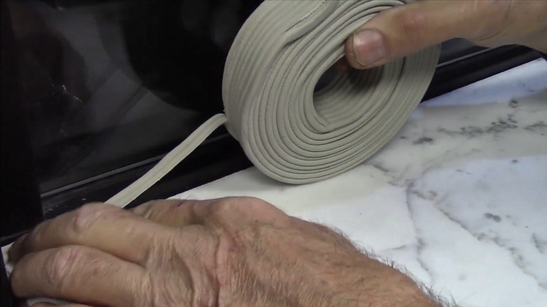 a person uses caulk cord to eliminate a gap between a counter and a window