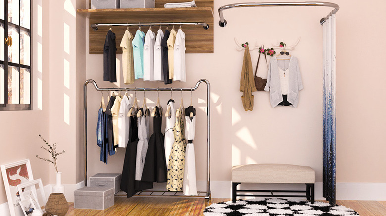 The U-Shaped Shower Curtain Rod being used as a dressing room area with clothes nearby