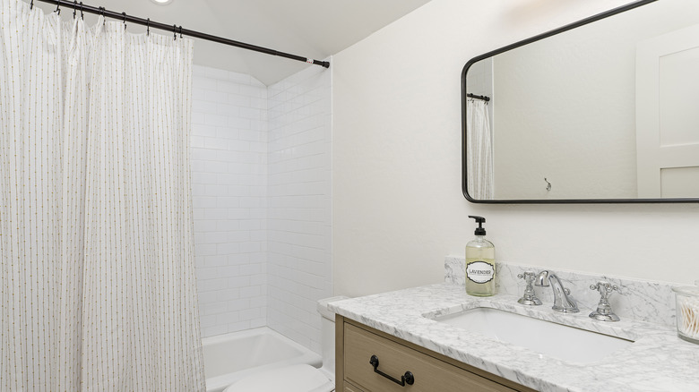 plain white bathroom with black shower curtain rod and hooks