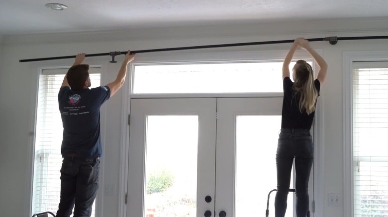 Couple hanging a DIY steel curtain rod