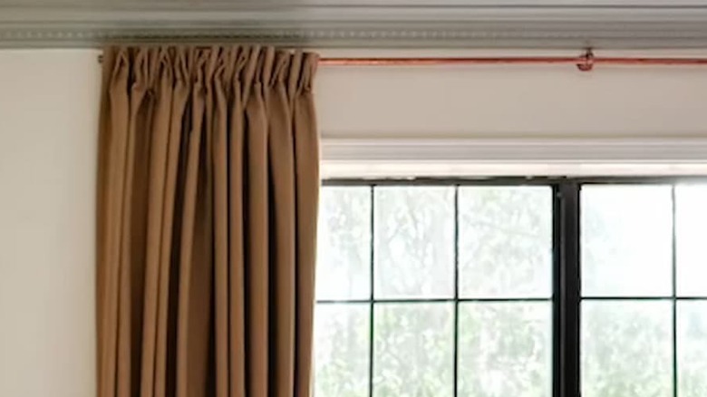 Curtains draped on copper curtain rod in front of a window
