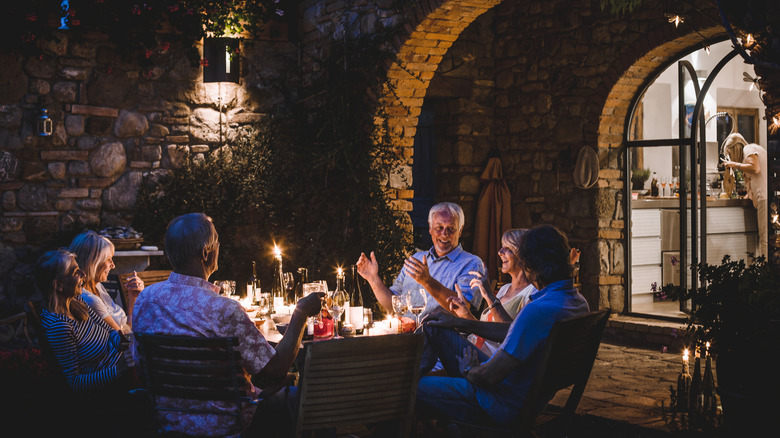 A group of adult friends dining on a patio at night.