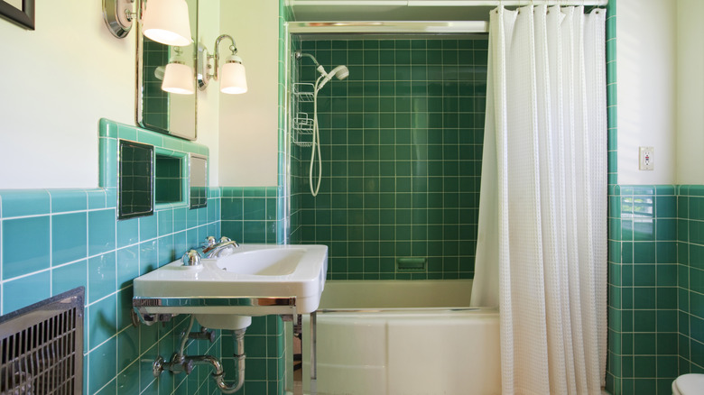 A small bathroom with colorful tiles and white shower curtain
