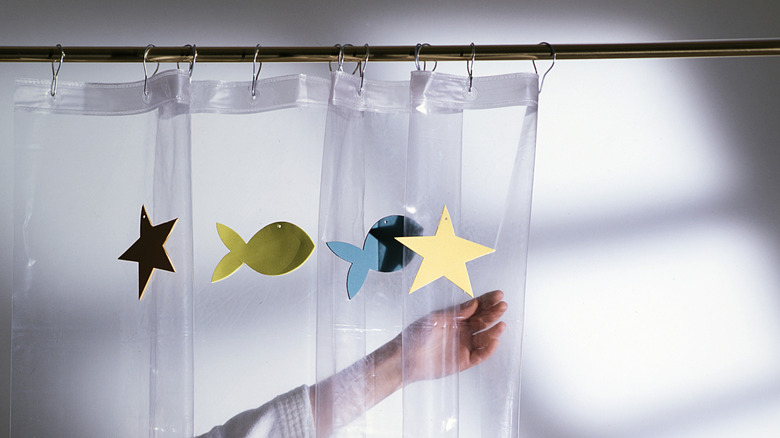 Hand pulling kid-theme shower curtain open.