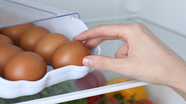 person taking an egg out of a fridge