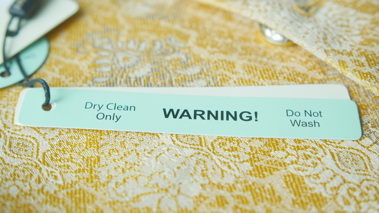 A dry clean only tag laying on a yellow garment