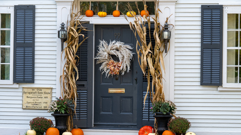 front door framed by dried cornstalks and pumpkins