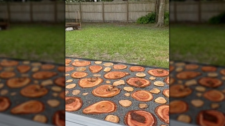 A patio area paved with cut logs surrounded by gray gravel