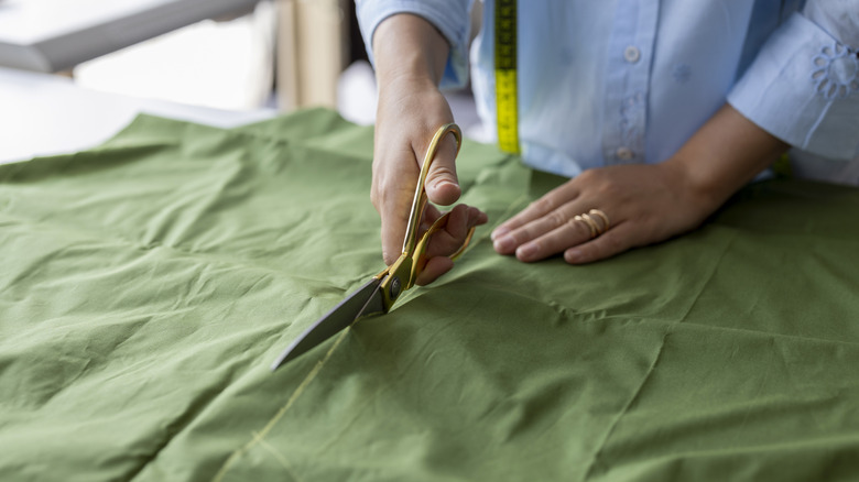 Person uses scissors to cut green cotton fabric to create a towel tie.