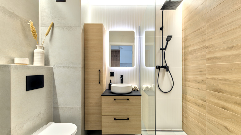 White bathroom with off-white cabinets and walk-in shower.