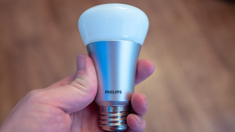 Person holding a Philips Hue smart light bulb
