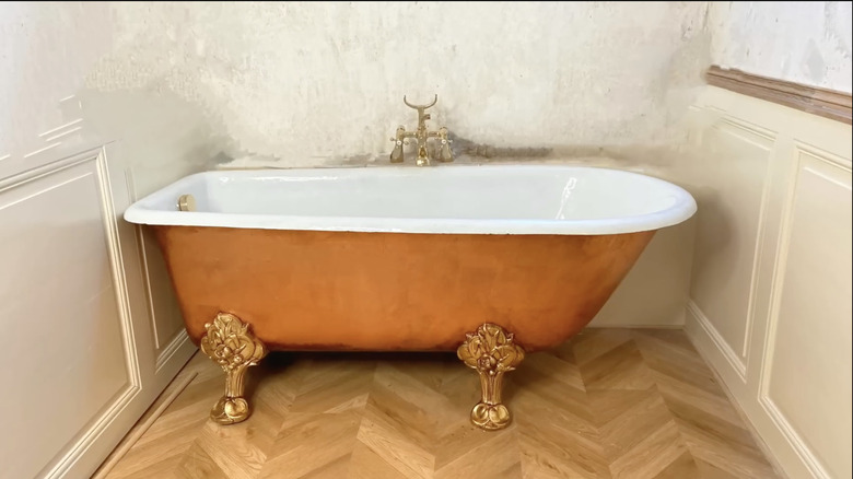 A cast-iron bathtub that got an upgrade to look like an old-world copper tub sits in a white bathroom.