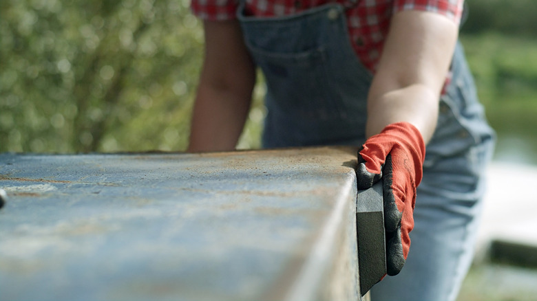 A person sanding down a rusty surface.