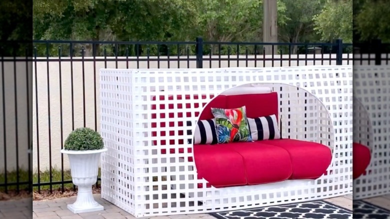 A white PVC lattice shade box surrounds a red and white DIY outdoor daybed.