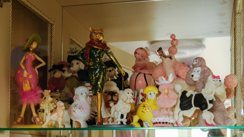 A glass shelf with a mirror behind it full of thrifted vintage collectibles