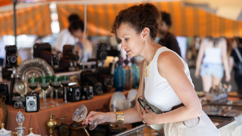 A woman shops at a market for vintage glassware.