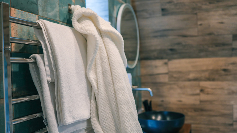 Bath towels and robe hung on a rack in a bathroom