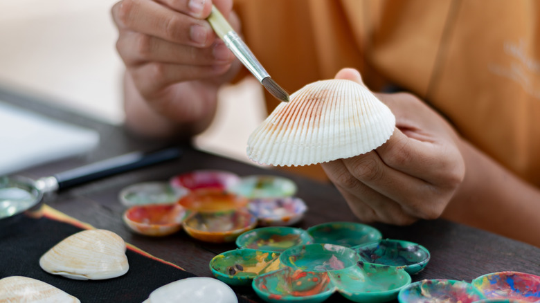 Hands painting shells with paint
