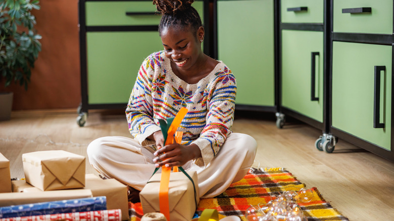 A woman sitting on the floor wrapping presents