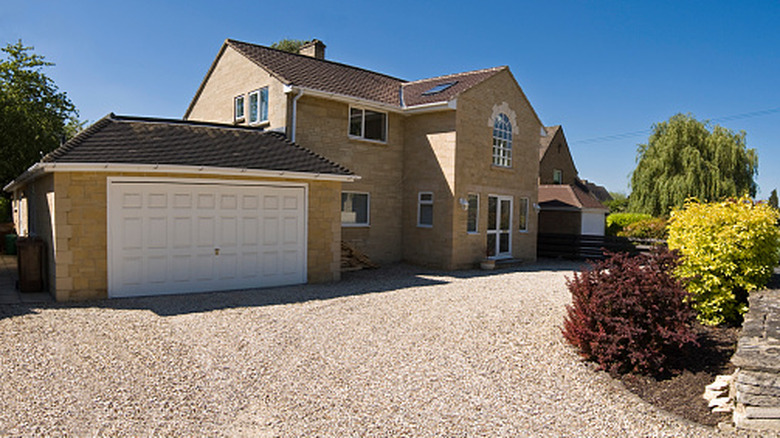 A modern home with an expansive gravel driveway