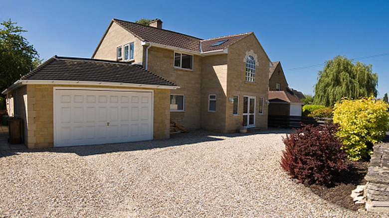 A modern home with an expansive gravel driveway