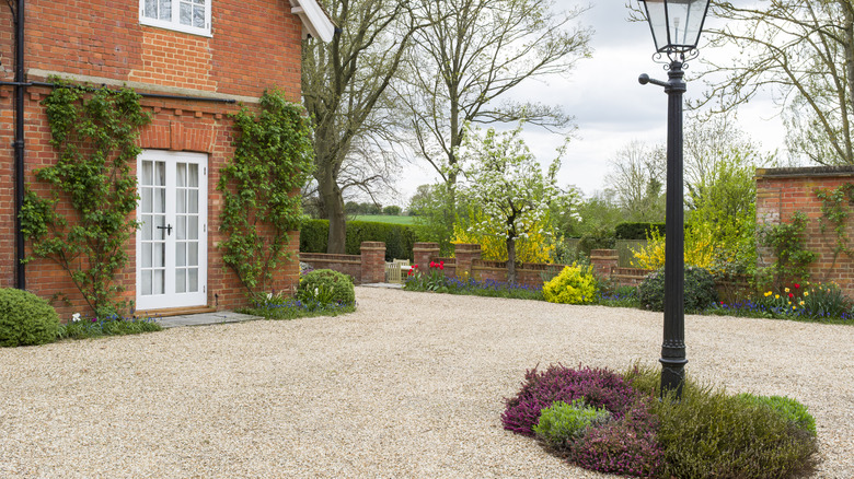 An attractive brick house with mature plantings and a gravel driveway