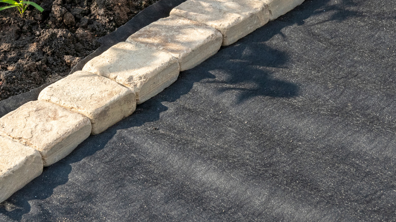 A paver border and geotextile ready for laying a gravel driveway