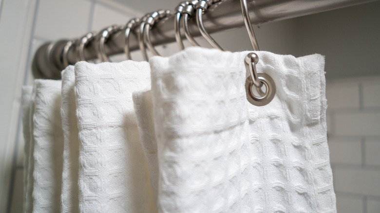 Decorative luxurious shower curtain on hooks.
