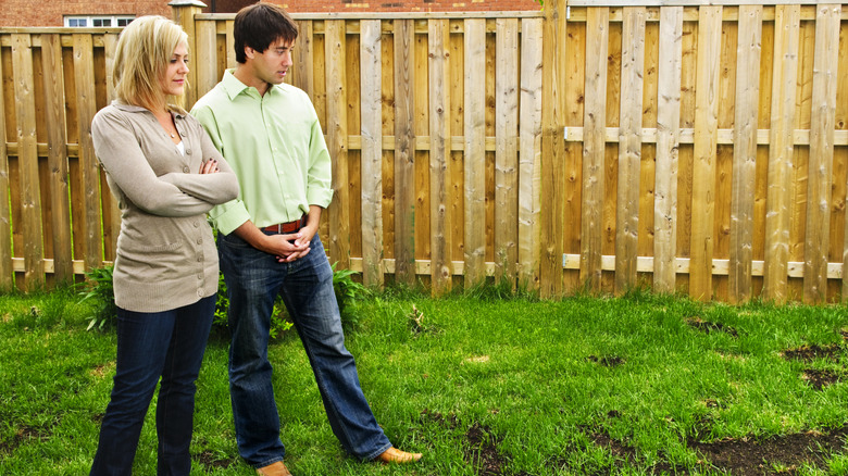 Man and woman looking at patchy lawn