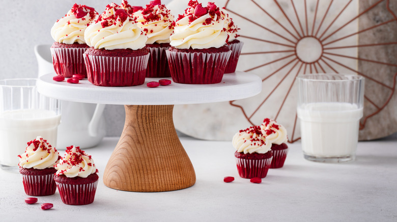 a wooden base cake stand with cupcakes displayed on and around it