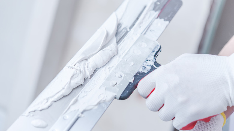 person holding a drywall knife