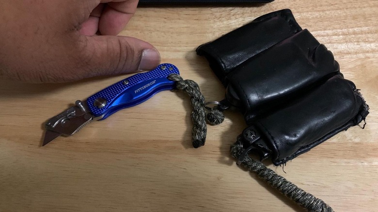 Pittsburgh's Mini Folding Lock-Back Utility Knife next to a person's thumb to show its small size