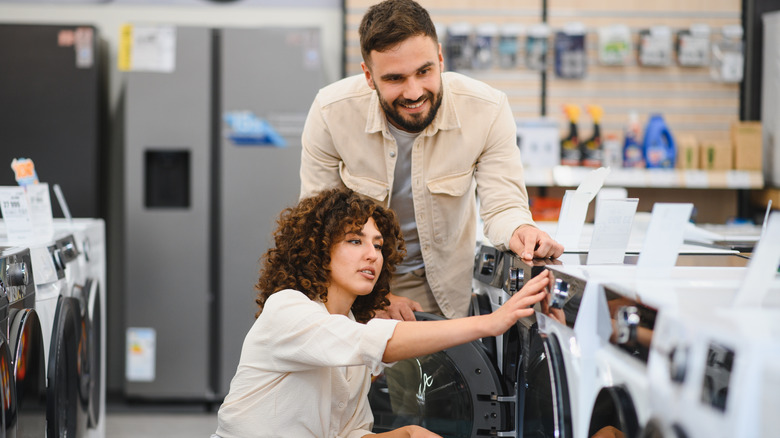 a couple selecting new washing machine in a home appliance store
