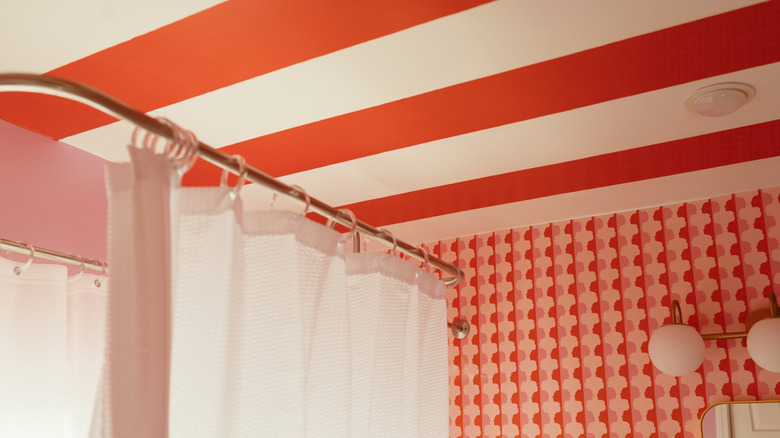 A bathroom with patterned walls and a striped ceiling.